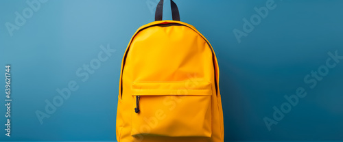 Yellow backpack filled with school supplies against a blue background.