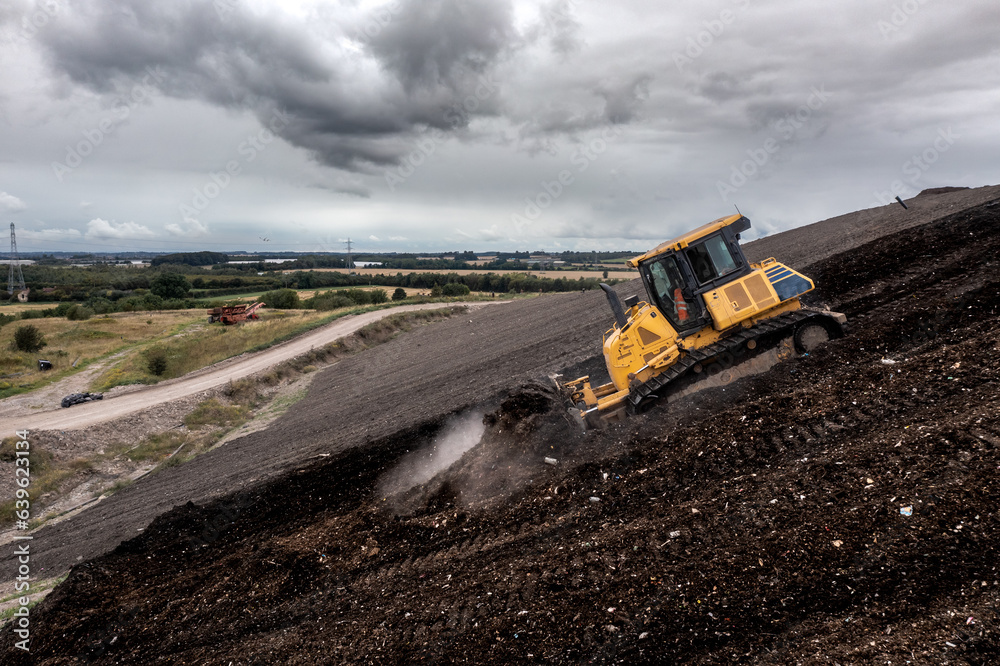 A bulldozer on a slope moving waste on a landfill site A bulldozer on a slope moving waste on a landfill site