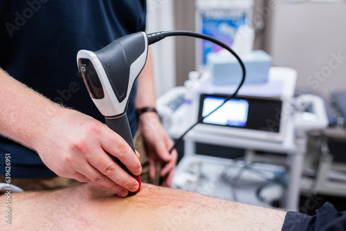 shockwave therapy to relieve pain and promote healing of injured tendons on leg photo