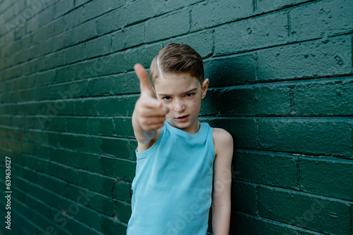 Portrait of a cool, young boy with serious attitude making a finger gun gesture photo