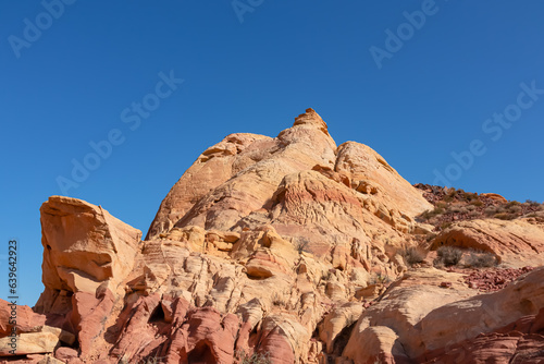 Scenic view of white Aztek sandstone rock formations in Petroglyph Canyon along Mouse Tank hiking trail in Valley of Fire State Park in Mojave desert, Nevada, USA. Hot temperature in arid vegetation photo