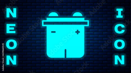 Glowing neon Car battery icon isolated on brick wall background. Accumulator battery energy power and electricity accumulator battery. Vector