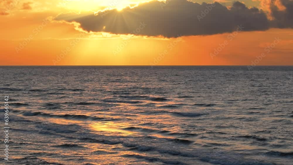 Beautiful sea waves with reflection of yellow and orange colored sunset light glowing, by the beach on the colorful sky clouds background, calm horizon scene, mid shot, slow motion. ProRes 422 HQ. Beautiful sea waves with reflection of yellow and orange colored sunset light glowing, by the beach on the colorful sky clouds background, calm horizon scene, mid shot, slow motion. ProRes 422 HQ.