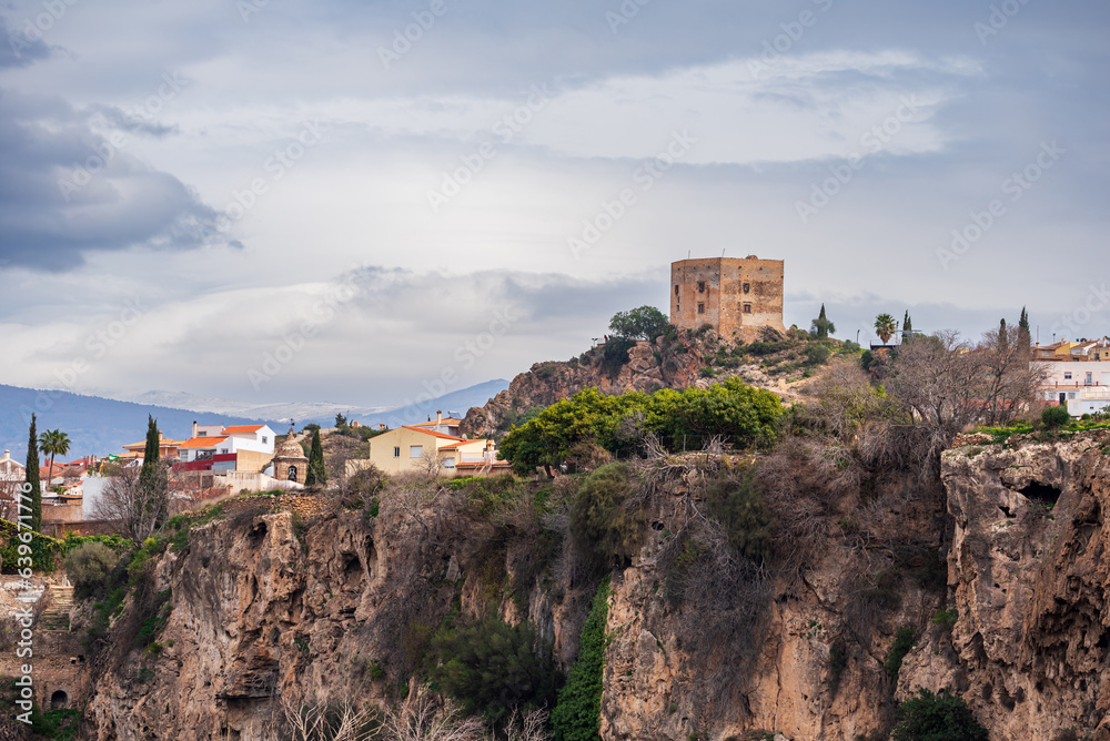 Velez de Benaudalla, in Granada, Spain, partial view of the town next to a ravine and its Moorish castle, with Sierra Nevada in the background.