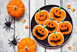 Plate of Halloween jack o lantern cookies. Above view  table scene on a white wood background.
