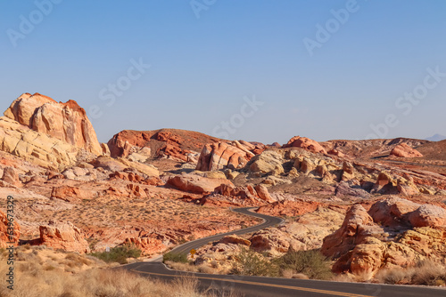 Photography Panoramic view of endless winding empty road in Valley of Fire State Park leading to red Aztec Sandstone Rock formations and desert vegetation in Mojave desert, Overton, Nevada, USA