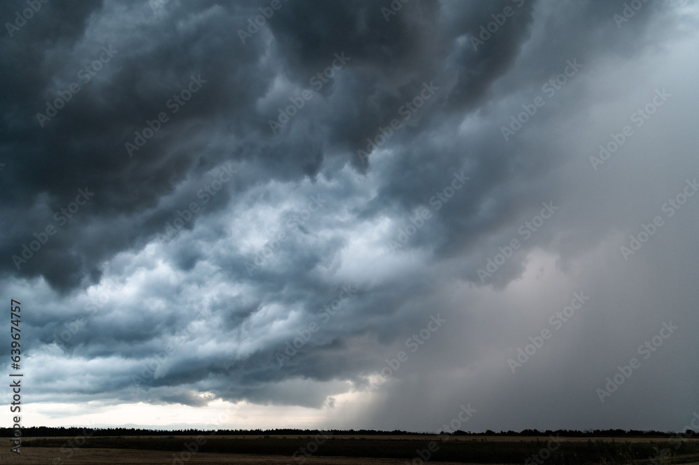 Menacing summer sky. Heavy dark blue rain clouds are on the left, and rain is already falling on the right. It got dark outside