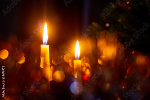 Two candles burning on a dark background with bokeh during Christmas and New Year celebrations