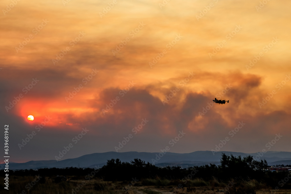 Devastating wildfire in Alexandroupolis Evros Greece, Aerial firefighting waterbombing planes, smoke covered the sky, sunset colors