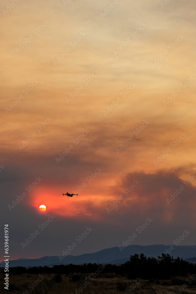 Devastating wildfire in Alexandroupolis Evros Greece, Aerial firefighting waterbombing planes, smoke covered the sky, sunset colors