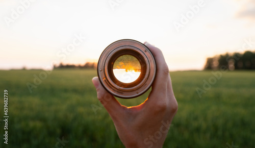 Looking to the green wheat field in the lights of evening sun. Point of view. Selective focus.
