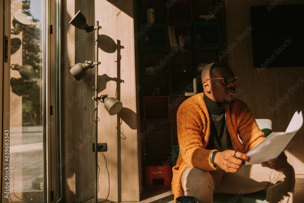 Tired black male person was distracted by something while reading a document Tired black male person was distracted by something while reading a document