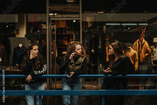 Two girls having a conversation while their long haired brunette friend is having a phone call