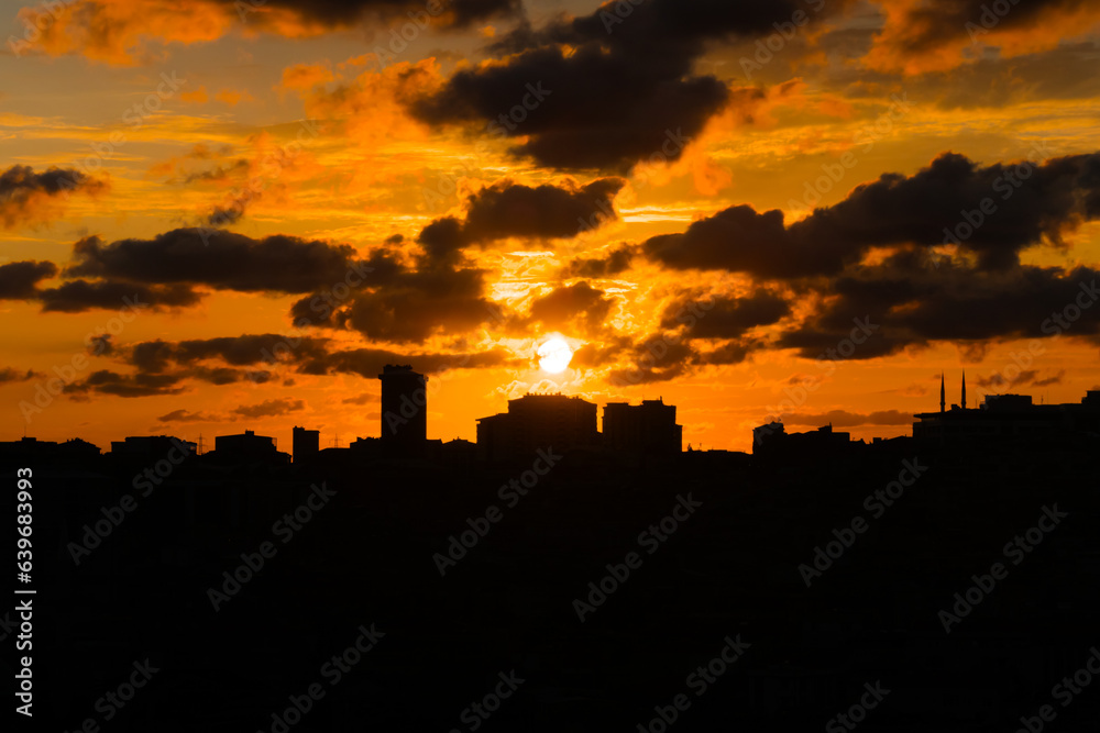 Dramatic cloudy sunset sky with clouds and the setting sun over the city of Istanbul, Turkey in the evening - apartment, residential buildings silhouettes. Urban, cityscape and cloudscape concept