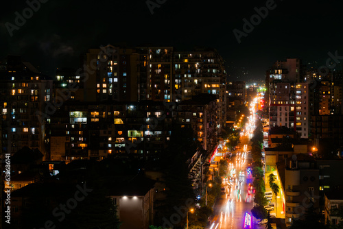 City highway traffic - street with typical residential buildings, fast moving cars and light trails in Batumi, Georgia at night. Rush hour, urban and transportation concept