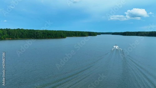 Smooth 4k drone footage of boat on lake in lush green forest with blue skies in Georgia, USA