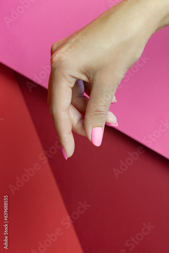 
Close up woman hand holding something small cosmetic product like a nail polish bottle isolated on white background with clipping path with manicure on red background. Female hand skin care concept