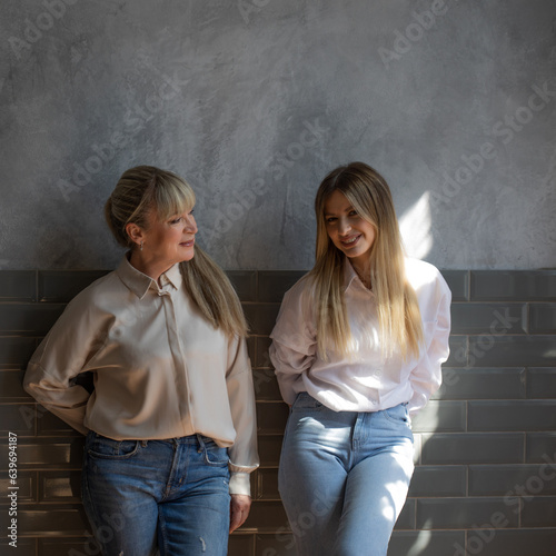 Happy family, women together. Mom and adult daughter smile at each other, studio photo in casual style © Ulia Koltyrina