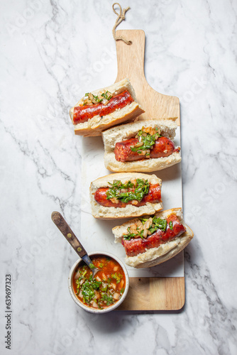 Chilean and Argentinian food. Traditional choripan with spicy pebre, chorizo sandwich with chorizo sausages and bread. photo