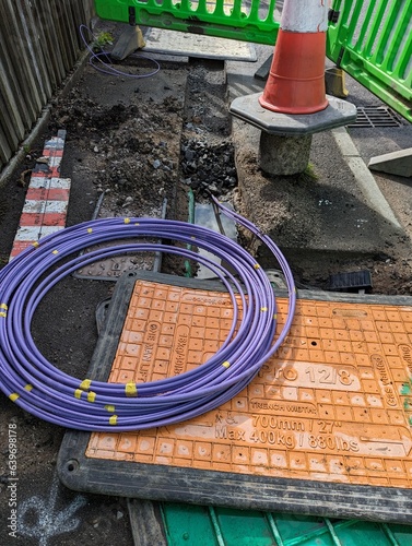 Fibre optic cable coming out of a trench curled up waiting to be installed for the UK gigabit broadband rollout being installed by the internet service providers ISPs across the country.