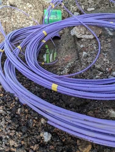 Fibre optic cable coming out of a trench curled up waiting to be installed for the UK gigabit broadband rollout being installed by the internet service providers ISPs across the country.