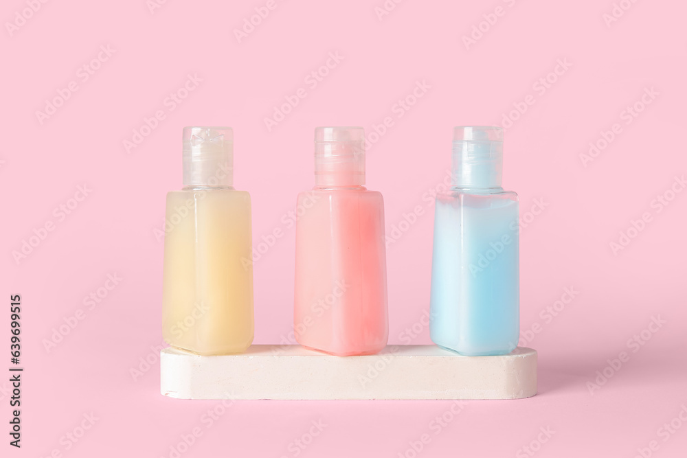 Plaster podium with bottles of cosmetic products on pink background Plaster podium with bottles of cosmetic products on pink background