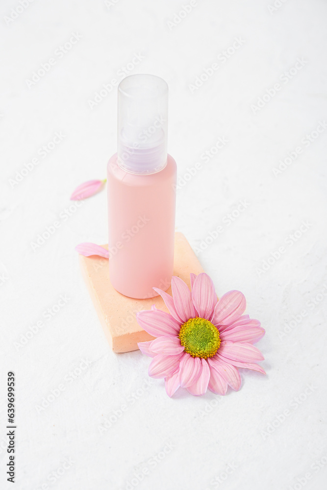 Plaster podium with bottle of cosmetic product and flower on light background Plaster podium with bottle of cosmetic product and flower on light background