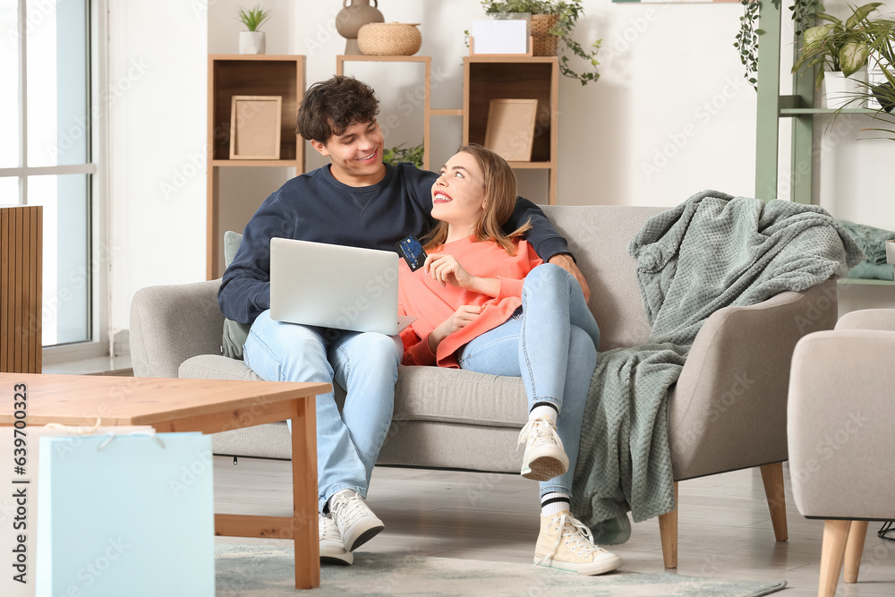 Young couple with laptop and credit card shopping online at home Young couple with laptop and credit card shopping online at home