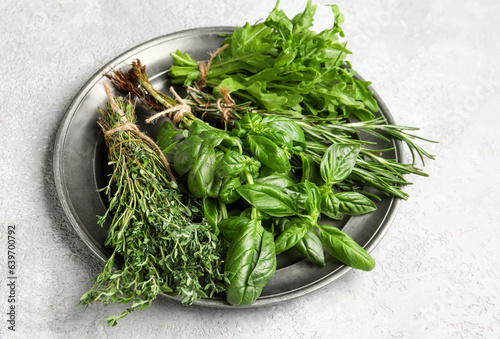 Plate with fresh aromatic herbs on light background