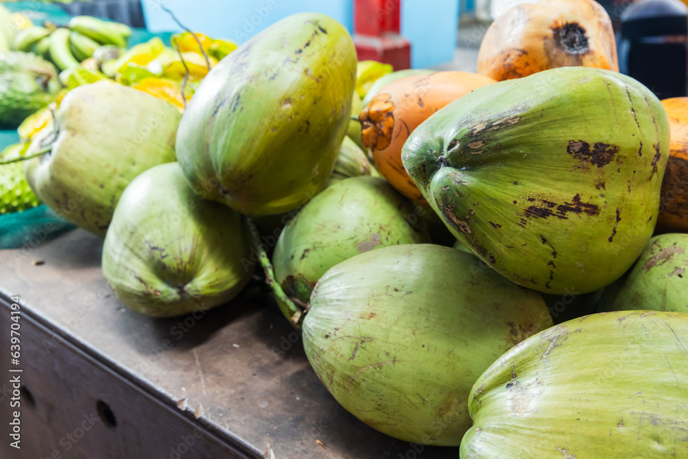Green coconuts are on a counter at local marketplace Green coconuts are on a counter at local marketplace