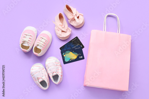 Composition with different baby booties, credit cards and shopping bag on lilac background