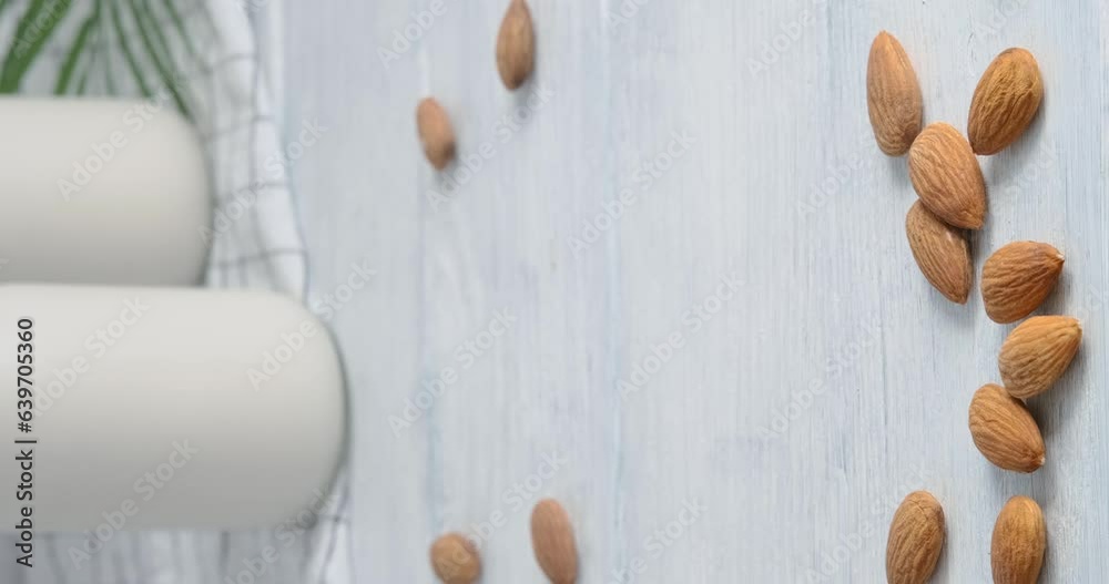 Person taking a glass with almond milk, Close-up video of vegan drink made of almond nuts placed on white table, 4k vertical video, slow motion footage Person taking a glass with almond milk, Close-up video of vegan drink made of almond nuts placed on white table, 4k vertical video, slow motion footage