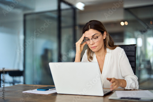 Fotografia Worried fatigued mature business woman wearing glasses having headache at work