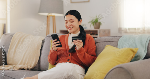 Happy woman, credit card and phone on couch online shopping, ecommerce and fintech easy payment. Asian person in China typing bank information on cellphone for discount or finance transaction at home photo