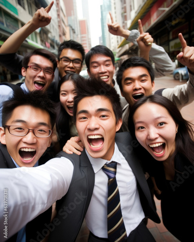 An energetic group of young Asian professionals gather for a group photo in the middle of a bustling street. They take turns brushing each other off and clapping each others shoulders