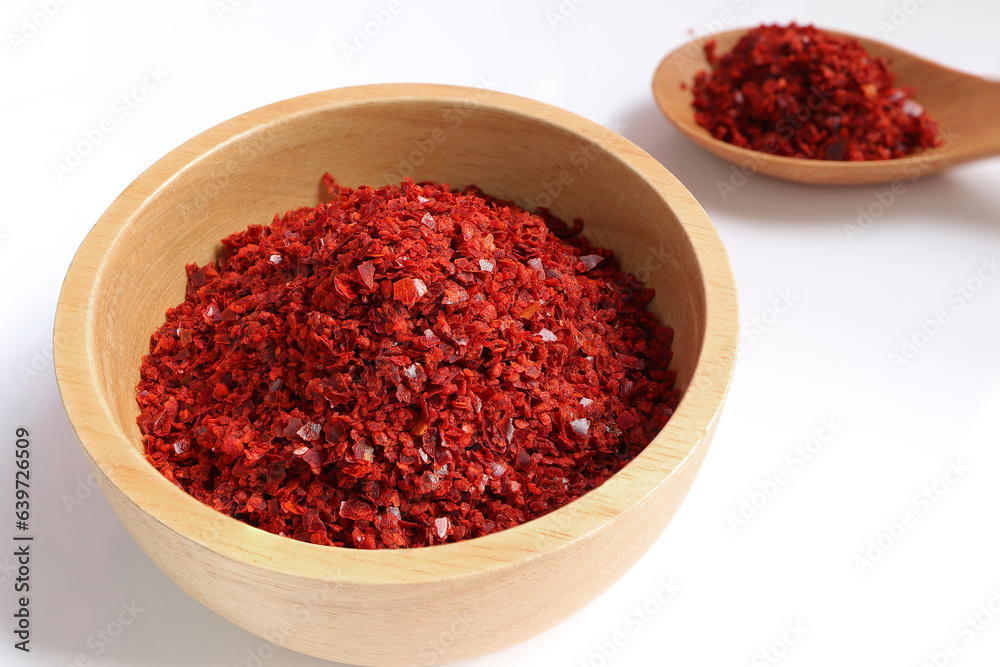 Red Chilli pepper seedless flakes in wooden bowl on white background. Organic red spicy korean. ingredients in Korea known as Gochugaru. used for kimchi, spicy fermented condiment in Korean food Red Chilli pepper seedless flakes in wooden bowl on white background. Organic red spicy korean. ingredients in Korea known as Gochugaru. used for kimchi, spicy fermented condiment in Korean food