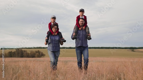 Mother and father farmers carry little boys on shoulders walking together