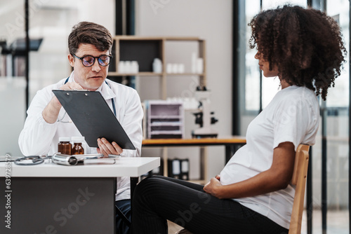 Male gynecologist doctor checking african american pregnant woman, Gynecology Consultation concept, examining belly stethoscope, obstetrician OB doctor special training in women health and pregnancy