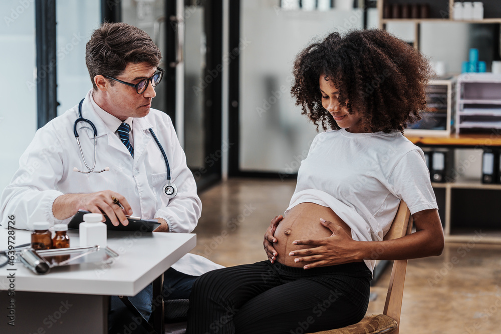 Fototapeta premium Male gynecologist doctor checking african american pregnant woman, Gynecology Consultation concept, examining belly stethoscope, obstetrician OB doctor special training in women health and pregnancy