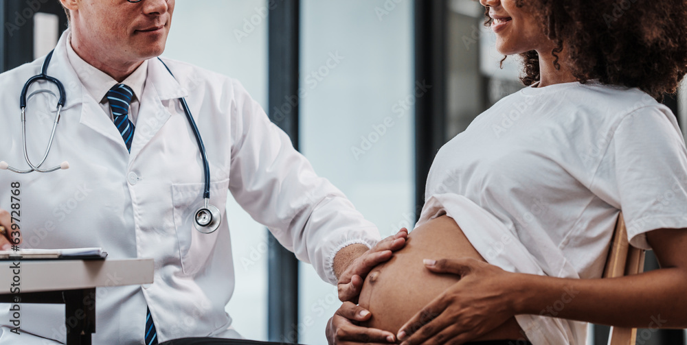 Obraz premium Male gynecologist doctor checking african american pregnant woman, Gynecology Consultation concept, examining belly stethoscope, obstetrician OB doctor special training in women health and pregnancy
