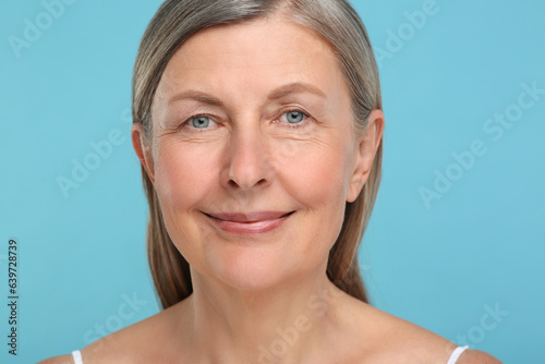Portrait of senior woman with aging skin on light blue background. Rejuvenation treatment