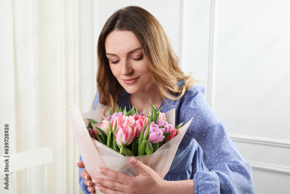 Happy young woman with bouquet of beautiful tulips indoors Happy young woman with bouquet of beautiful tulips indoors