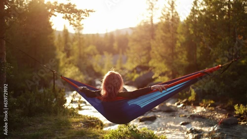 A girl in a hammock near a mountain stream. Calmness, rest and tranquility