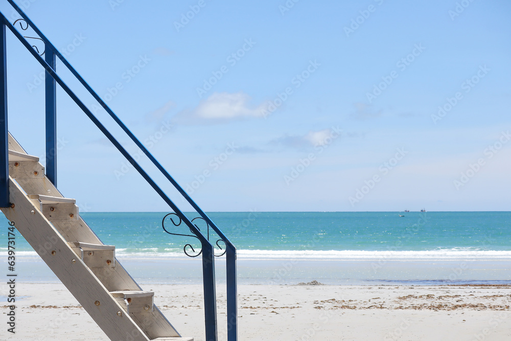 Selective focus on wooden stairs next to a beach. Side view of white wooden stairs and blurred beach background. Selective focus on wooden stairs next to a beach. Side view of white wooden stairs and blurred beach background.