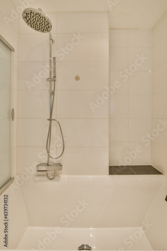 a white bathtub in a bathroom with a shower head mounted on the wall next to it is a glass door