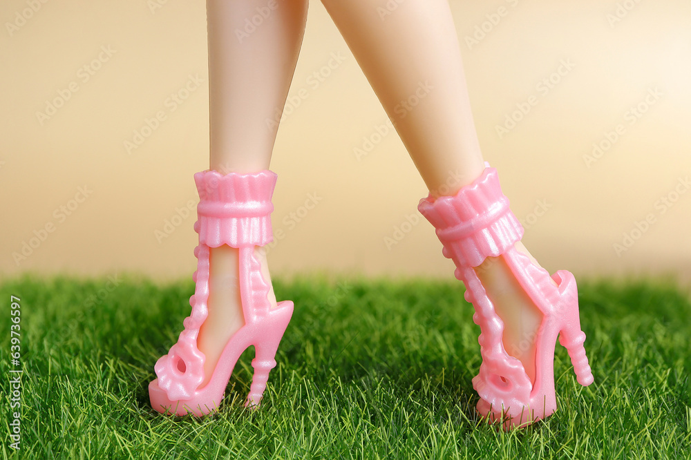 Plastic toy dolls with high heels. Legs of dolls in heel shoes on beige colored background. fashion and beauty concept