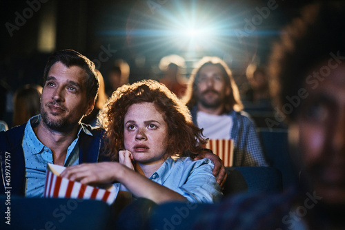 Young couple watching a movie and eating popcorn in a movie theater