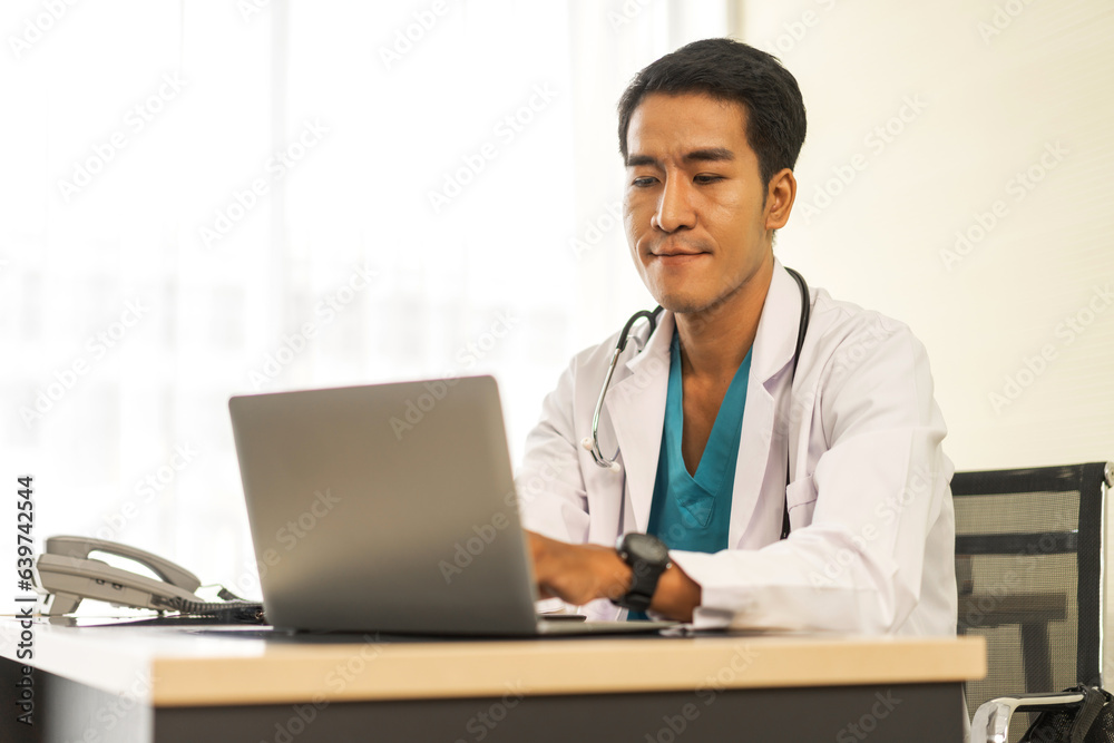 Asian man doctor wearing uniform with stethoscope working with laptop computer with virtual screen medical technology in hospital.healthcare technology and medicine