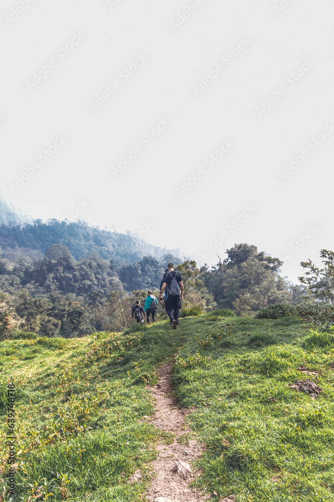 vertical shot of young hiker walking through a rural area on a cloudy day on the slopes of the Turrialba Volcano