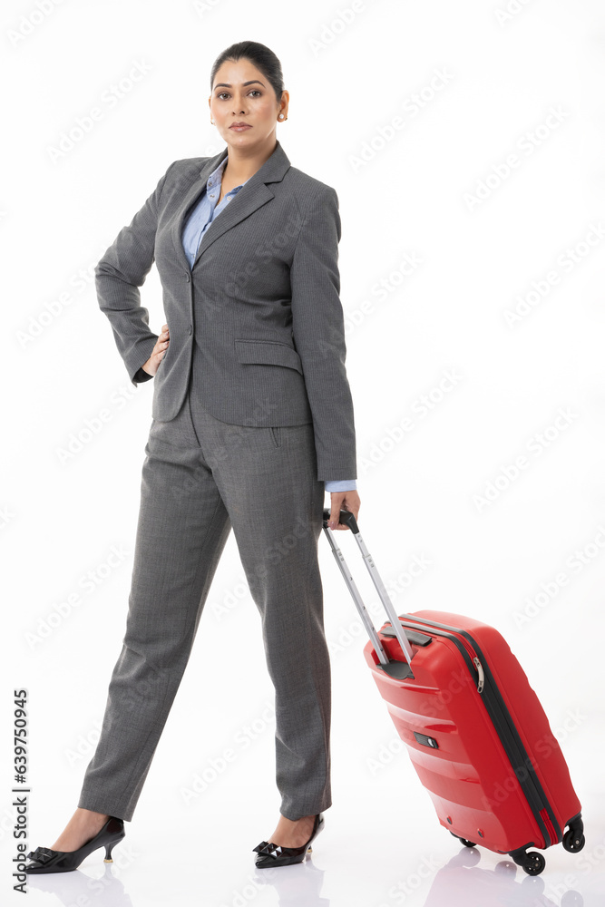Full length of confident female professional manager with suitcase and standing against white background. Full length of confident female professional manager with suitcase and standing against white background.